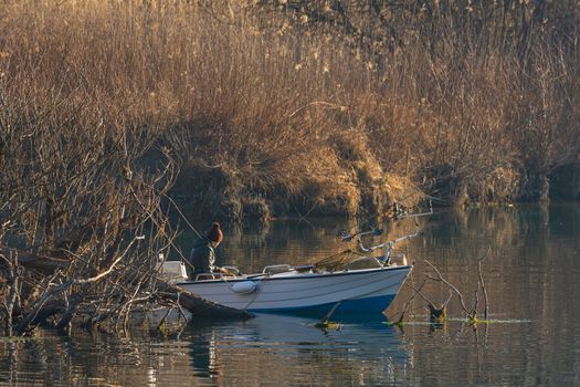 Fisherman on a boat by the river in the early morning