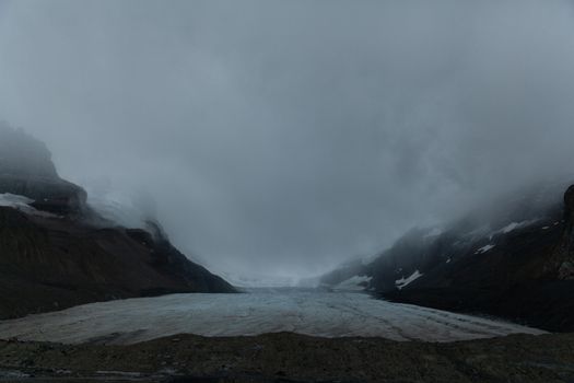 Athabasca glacier covered with fog sliding from the mountains, Alberta, Canada