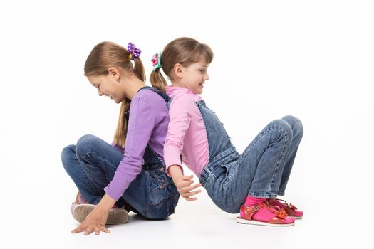 Children sitting on the floor have fun pushing their backs, isolated on white background