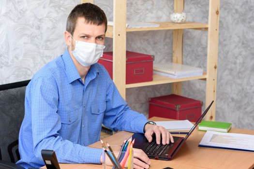 Portrait of an office worker in a medical mask at a desk