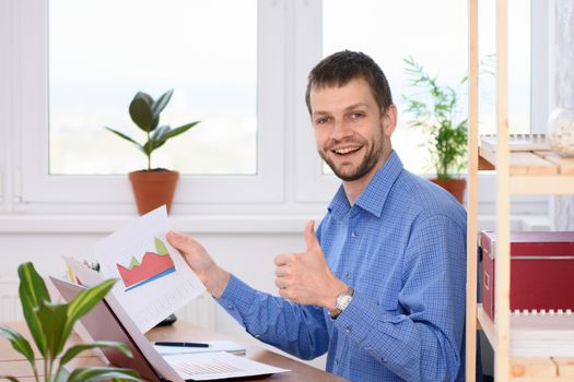 Young businessman shows charts and thumb up