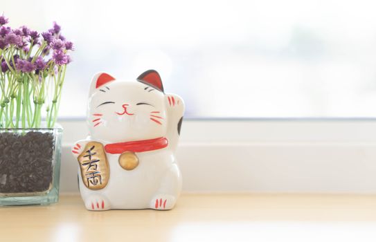 Maneki neko lucky cat show text on hand meaning rich on table, select focus
