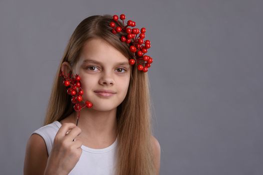 Portrait of a beautiful ten year old girl with a bunch of berries in her hand and hair