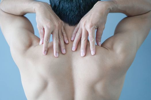 Closeup man hand holding shoulder with pain on blue background, health care and medical concept
