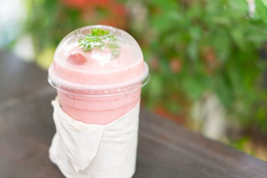 Closeup  strawberry smoothie with green nature background, selective focus