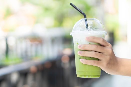 Close up glass of ice matcha green tea on hand, selective focus