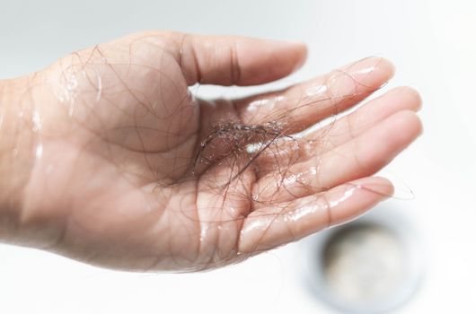 Closeup Hair loss on woman hand in the bathroom