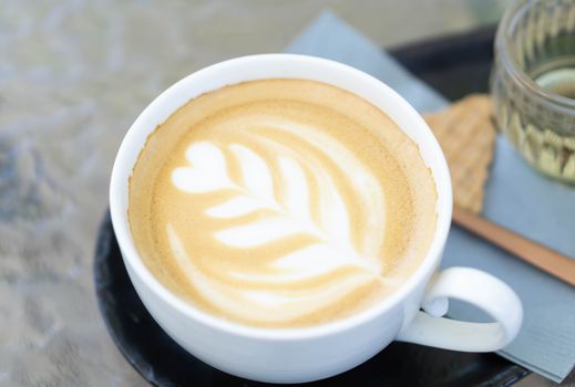 Closeup glass of latte art coffee tulip shape on wood background with vintage color, selective focus