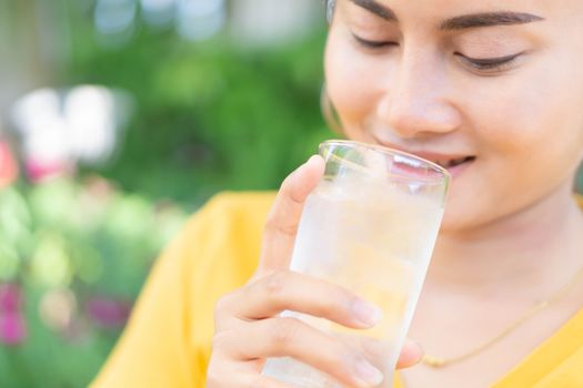 Close up woman drinking pure water from glass with light in the morning, Selective focus