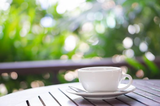 Closeup hot americano coffee on glass table with green nature background