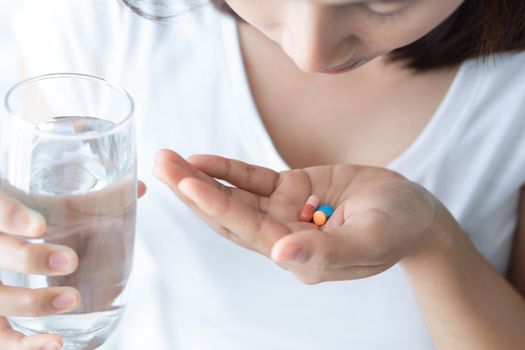 Closeup woman hand holding pills and glass of water, health care and medical concept, selective focus