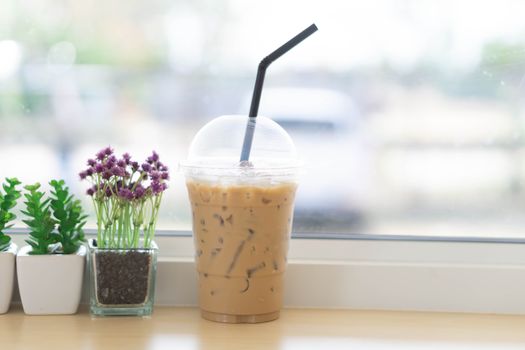 Closeup glass of ice coffee with flower pot in the coffee shop