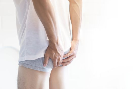Closeup man holding bladder with pee pain in the toilet, selective focus
