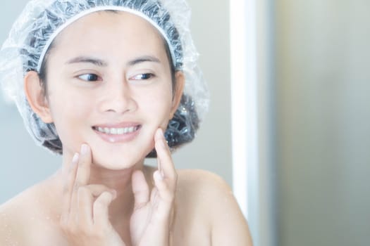 Close up woman looking her face in the mirror with smiling after bath, health care and beauty