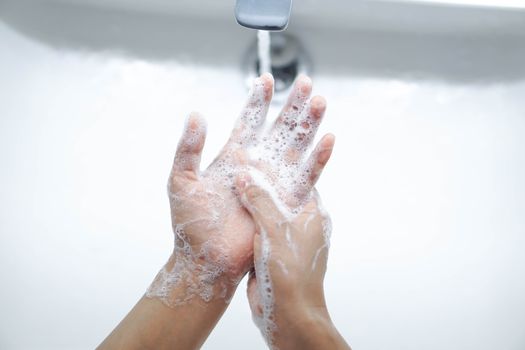 Closeup woman's hand washing with soap in bathroom, selective focus