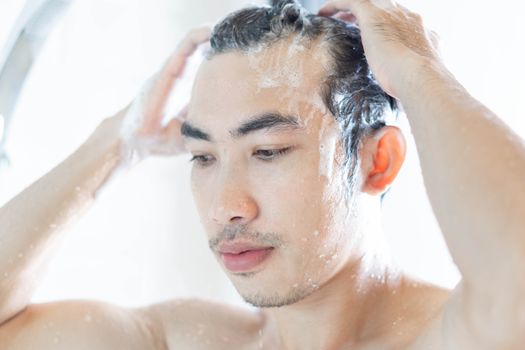 Closeup young man washing hair with with shampoo in the bathroom, vintage tone, selective focus