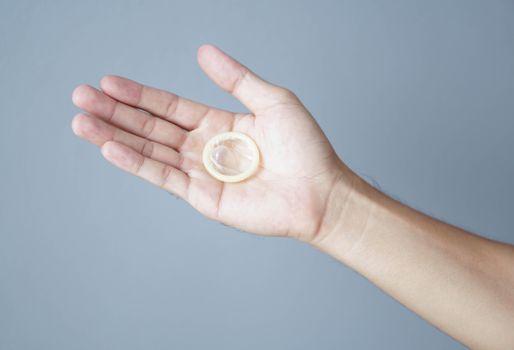 Close up woman hand holding condom lying on white bed, health care and medical concept