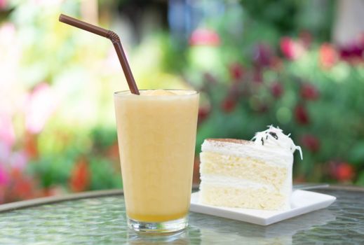 Closeup passion fruit smoothie and milk cake with green nature background, selective focus