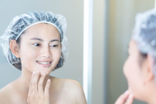 Close up woman looking her face in the mirror with smiling after bath, health care and beauty