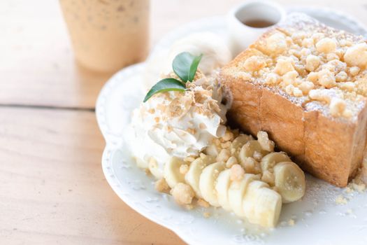 Honey toast dessert with ice coffee on wood table