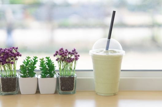 Clsoeup glass of avocado frappe or smoothie with flower pot in the coffee shop, selective focus