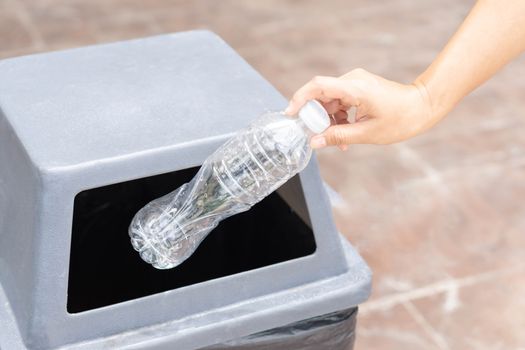 Close up hand holding garbage plastic bottle into recycle trash bin, selective focus