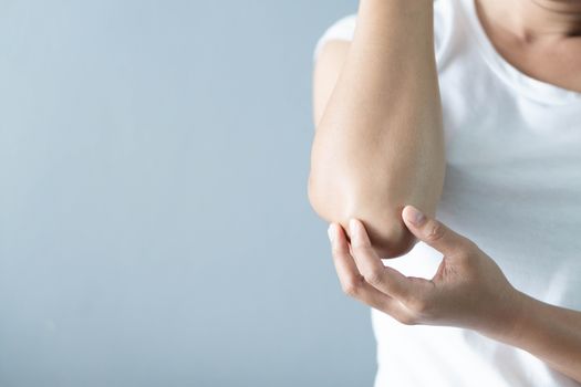 Closeup woman hand holding elbow with pain lying on bed, health care and medical concept