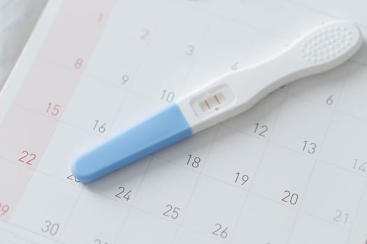 Pregnancy test on calendar background, health care concept