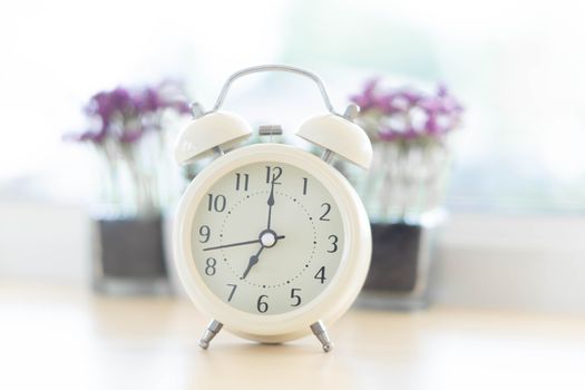 Alarm clock on white table with soft light in the morning, selective