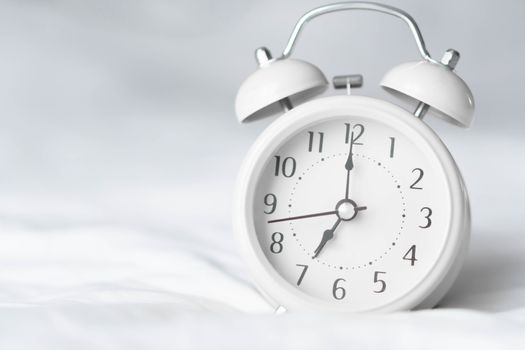 Alarm clock on wooden table for wake up time with light from window, selective focus
