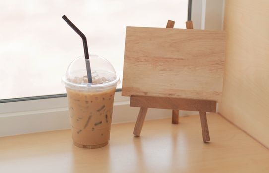 closeup glass of ice coffee with empty wooden sign for text in the coffee shope