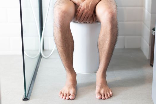 Closeup man sitting on toilet in the morning, selective focus
