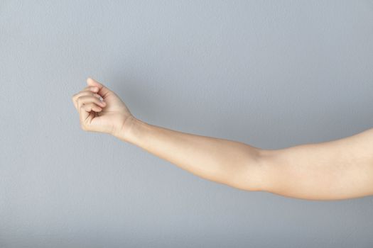 woman hand with clenched fist on grey background, health care and medical concept