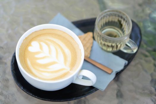 Closeup glass of latte art coffee tulip shape on wood background with vintage color, selective focus