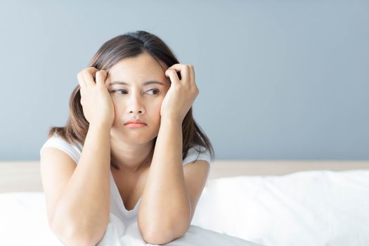 Closeup woman sitting on bed in the bedroom with thinking or depressed feeling, selective focus