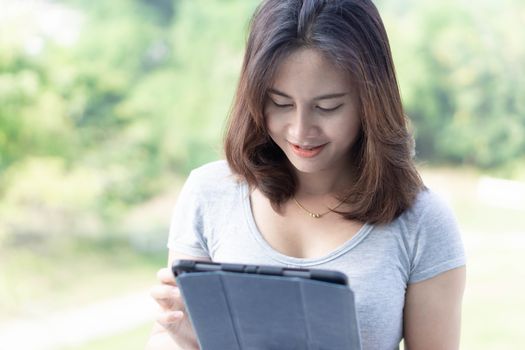 Closeup asian woman using digital tablet with green nature background