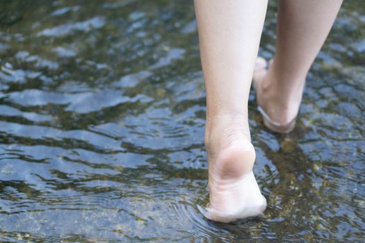 Woman feet walking on the water in the river for relax feeling