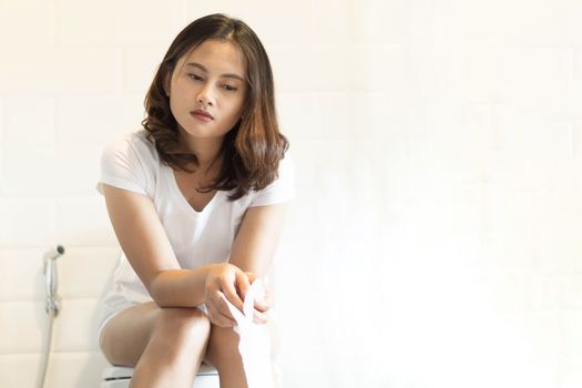 Closeup woman sitting on toilet in the morning with depressed feeling, selective focus