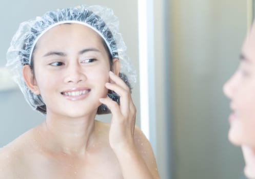 Close up woman looking her face in the mirror with smiling after bath, health care and beauty