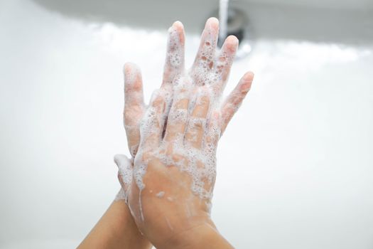 Closeup woman's hand washing with soap in bathroom, selective focus