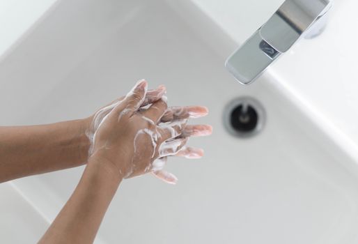 Closeup woman's hand washing with soap in bathroom, selective focus