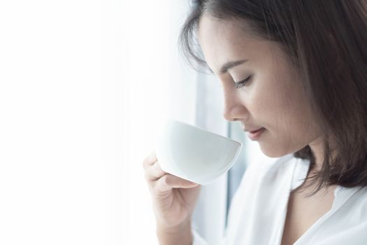 Closeup woman hand holding glass of hot americano coffee, selective focus, vintage tone