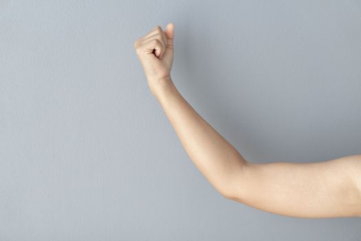 woman hand with clenched fist on grey background, health care and medical concept