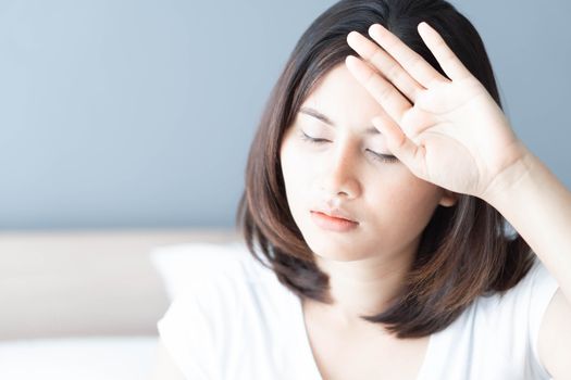 Woman hand holding forehead with sick and headache lying on white bedroom, health care and medical