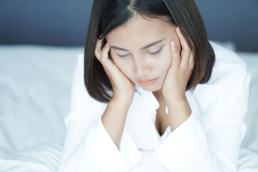 Closeup woman sitting on bed in the bedroom with thinking or depressed feeling, selective focus