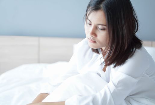 Closeup woman sitting on bed in the bedroom with depressed feeling, selective focus