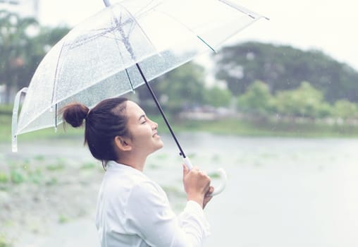 Closeup smiling and happy woman with umbrella in the rain season, vintage tone