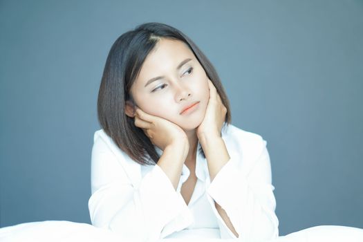 Closeup woman sitting on bed in the bedroom with thinking or depressed feeling, selective focus