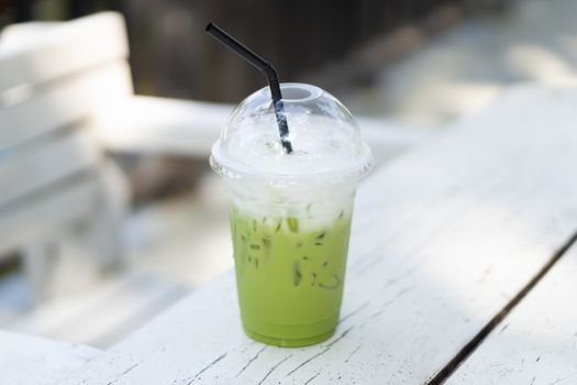 Close up glass of ice matcha green tea on wood table, selective focus