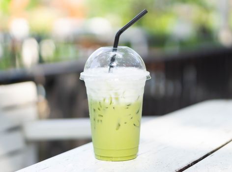 Close up glass of ice matcha green tea on wood table, selective focus